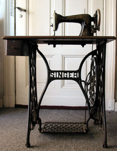 Typical Singer treadle sewing machine in table with iron stand.