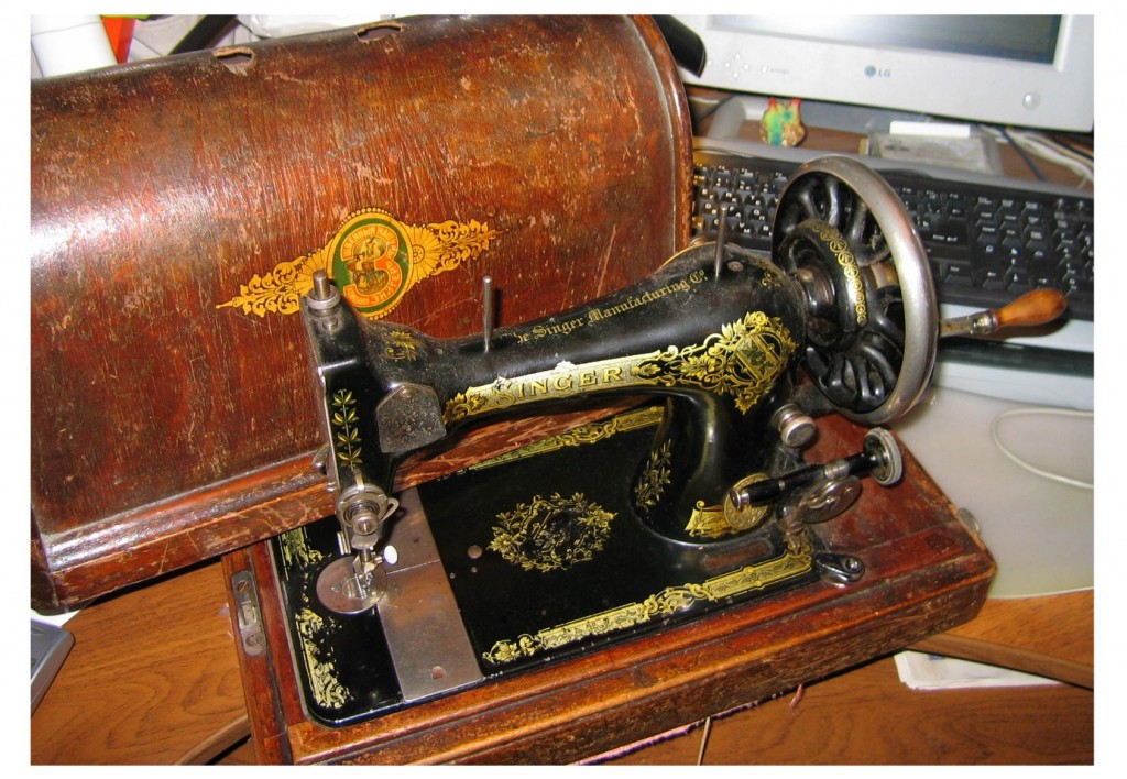 Hand-operated Singer sewing machine.  "Singer" on the wooden case is printed in the Cyrillic alphabet, while the machine itself is not.