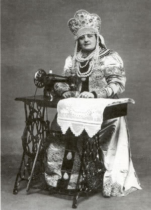 Singer ads portrayed women of many countries sewing at their machines.  This is a woman in traditional Russian costume, including a headdress in reality far too heavy to allow bending over her work.